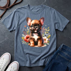Blue t-shirt with a dog graphic on a dark surface with shoes and jeans.
