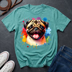 Teal t-shirt with a colorful pug design on a dark surface with shoes and jeans.