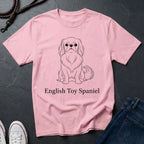 Pink t-shirt with an English Toy Spaniel graphic and text on a dark surface.