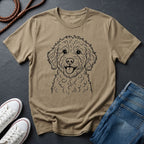 Beige Comfort Colors t-shirt with a dog illustration on a dark surface with shoes and jeans.