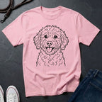 Pink Comfort Colors t-shirt with a dog illustration on a dark surface with shoes and jeans.
