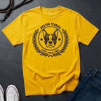 Yellow Comfort Colors t-shirt with Boston Terrier graphic and text on a dark surface with jeans and shoes.