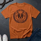 Orange Comfort Colors t-shirt with Boston Terrier graphic and text on a dark surface with jeans and sneakers.