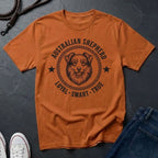 Orange Comfort Colors t-shirt with Australian Shepherd graphic and text on a dark surface