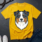 Yellow Comfort Colors t-shirt with a dog graphic on a dark surface with shoes and jeans.