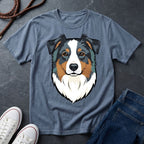 Blue Comfort Colors t-shirt with a dog graphic on a dark surface with shoes and jeans.