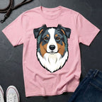 Pink Comfort Colors t-shirt with a dog graphic on a dark surface with jeans and shoes.
