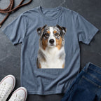 Blue Comfort Colors t-shirt with a dog graphic on a dark surface with shoes and jeans.
