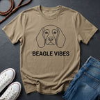 Beige Comfort Colors t-shirt with beagle graphic and 'BEAGLE VIBES' text on a dark surface with shoes and jeans.