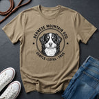 Beige Comfort Colors t-shirt with Bernese Mountain Dog graphic and text on a dark surface with shoes and jeans.