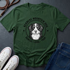 Green Comfort Colors t-shirt with Bernese Mountain Dog graphic and text on a dark surface with shoes and jeans.