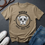 Beige Comfort Colors t-shirt with boxer dog graphic and text on a dark surface with shoes and jeans.