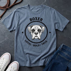 Blue Comfort Colors t-shirt with boxer dog graphic and text on a dark surface with shoes and jeans.
