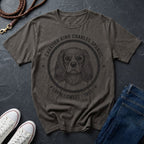 Gray Comfort Colors t-shirt with a dog illustration and heart design, placed on a dark surface with shoes and jeans.