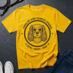 Yellow Comfort Colors t-shirt with Cavalier King Charles Spaniel design on a dark surface
