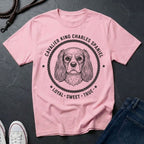 Pink Comfort Colors t-shirt with Cavalier King Charles Spaniel design and text on a dark surface.