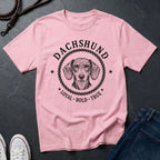 Pink Comfort Colors t-shirt with dachshund graphic and text on a dark surface