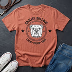 Coral Comfort Colors t-shirt with English Bulldog graphic and text on a dark surface with shoes and jeans.