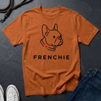 Orange Comfort Colors t-shirt with a dog illustration and 'FRENCHIE' text on a dark surface.