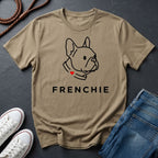 Beige Comfort Colors t-shirt with a dog illustration and 'FRENCHIE' text on a dark surface with shoes and jeans.