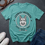 Teal Comfort Colors t-shirt with German Shepherd graphic and text on a dark surface with shoes and jeans.