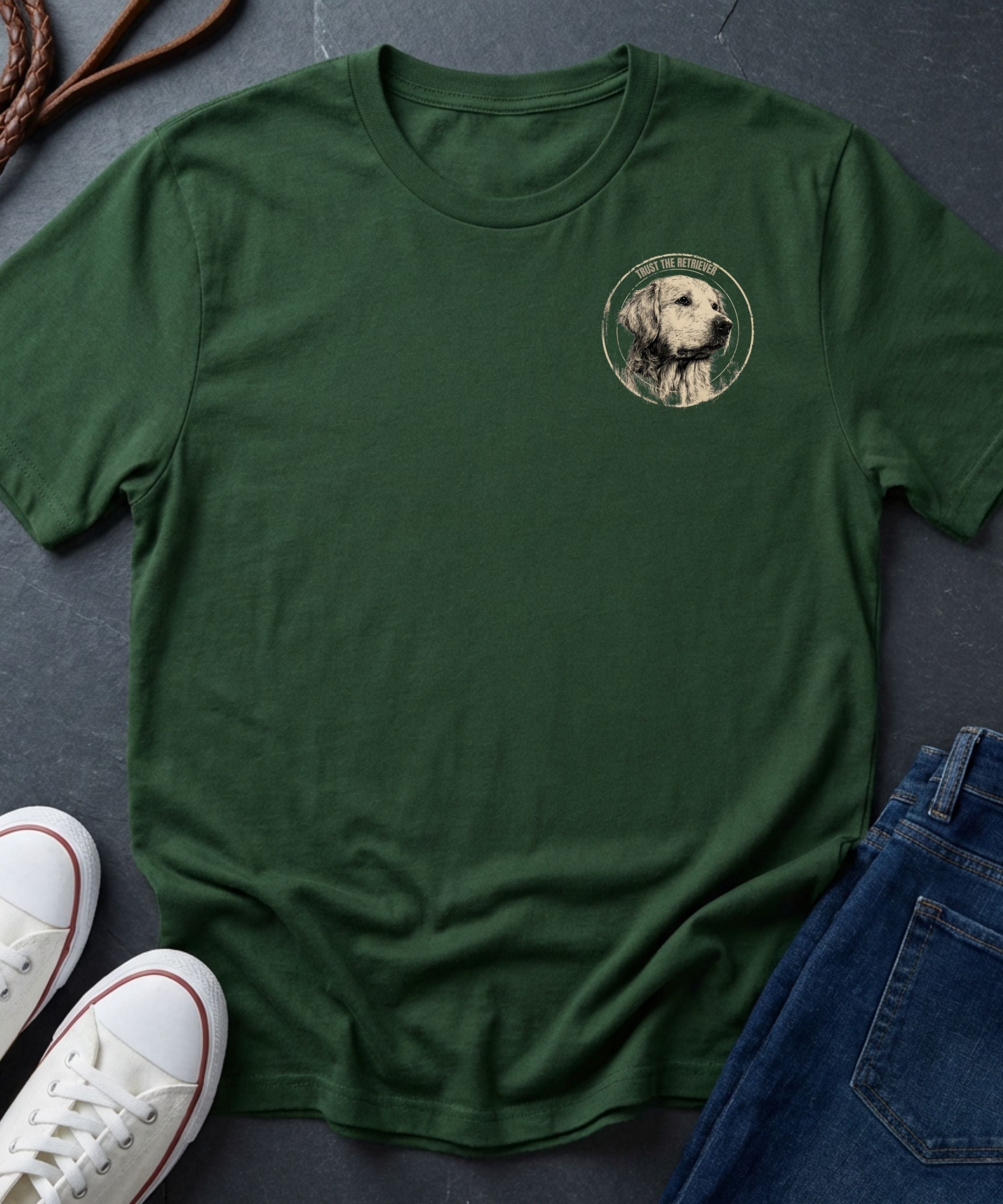 Green Comfort Colors t-shirt with a dog graphic on a dark surface with shoes and jeans.