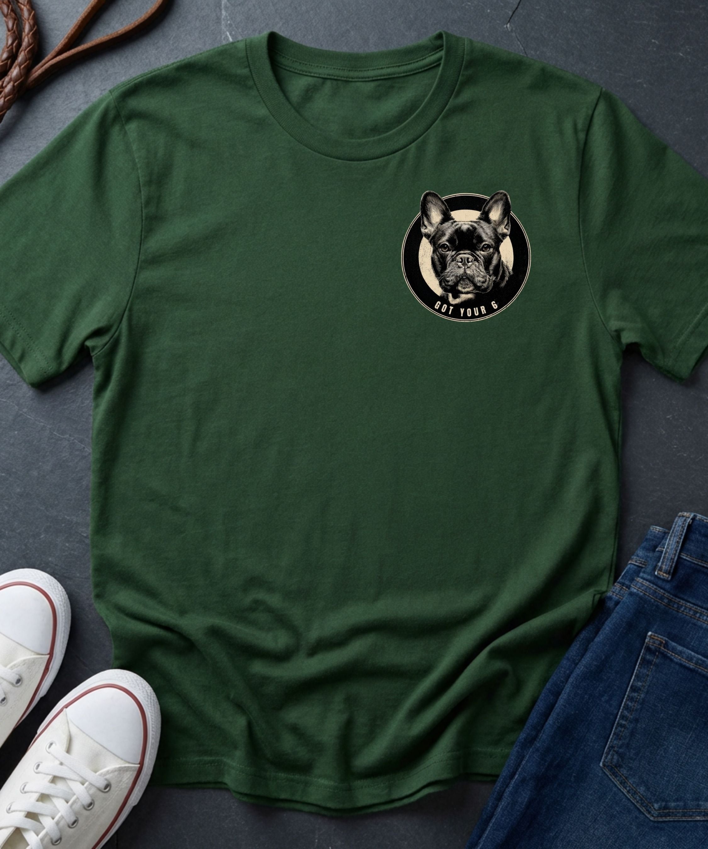 Green Comfort Colors t-shirt with a dog graphic on a gray surface with shoes and jeans.