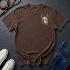 Brown Comfort Colors t-shirt with a dog graphic on a dark surface with shoes and jeans.
