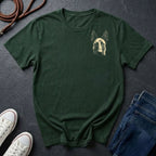 Green Comfort Colors t-shirt with a dog graphic on a dark surface with shoes and jeans.