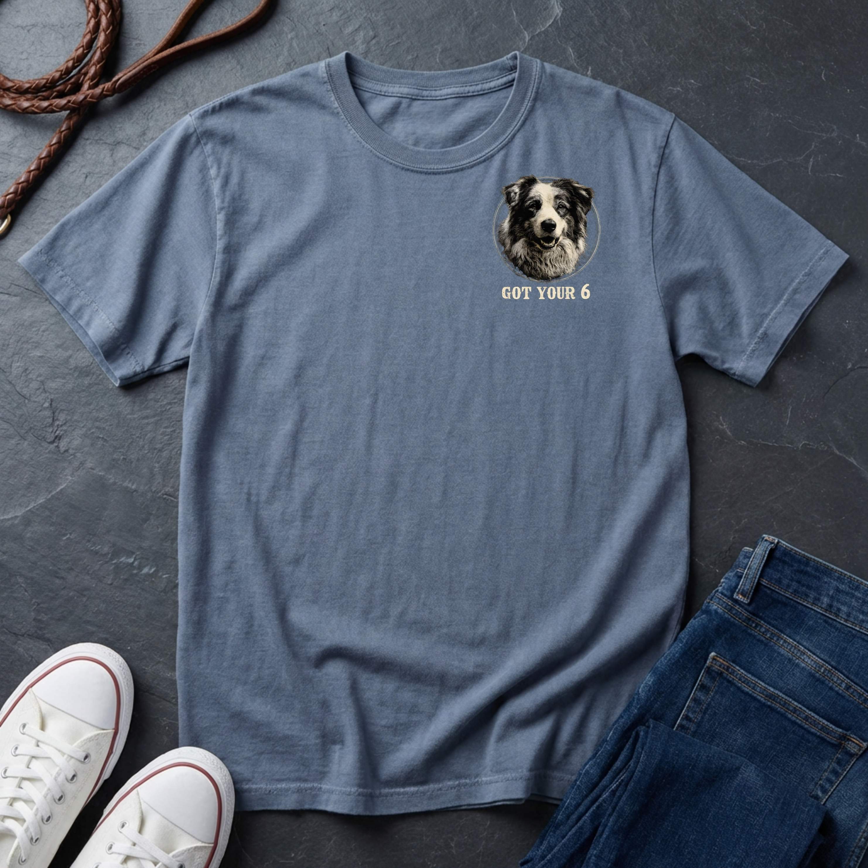 Blue Comfort Colors t-shirt with a dog graphic and text on a dark surface with shoes and jeans.