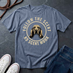 Blue Comfort Colors t-shirt with a dog graphic and text 'Follow the Scent K9 Scent Work' on a dark surface with shoes and jeans.