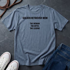 Blue Comfort Colors t-shirt with 'GOLDEN RETRIEVER MOM THE WOMAN THE MYTH THE LEGEND' text on a dark surface with shoes and jeans.