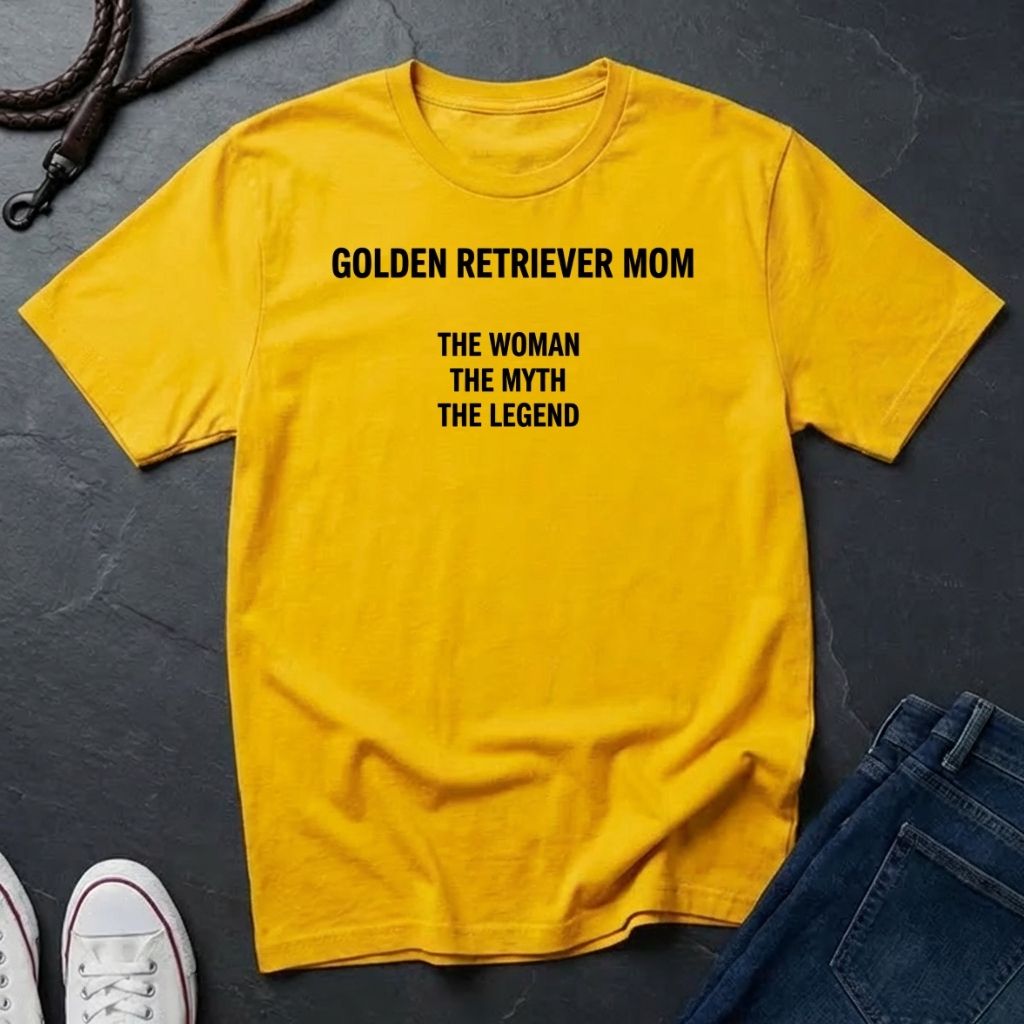 Yellow Comfort Colors t-shirt with text 'GOLDEN RETRIEVER MOM THE WOMAN THE MYTH THE LEGEND' on a dark surface.