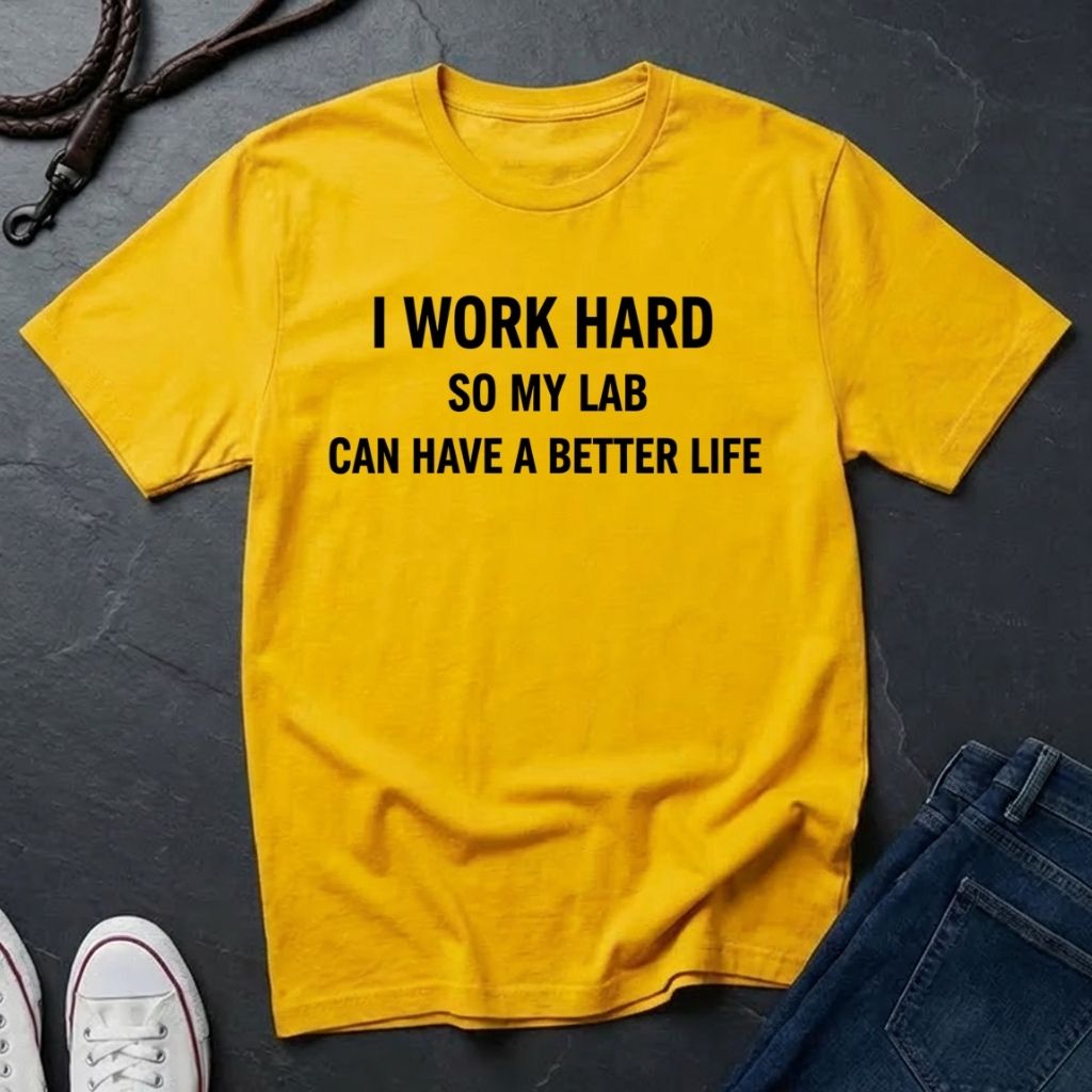 Yellow Comfort Colors t-shirt with text 'I work hard so my lab can have a better life' on a dark surface.