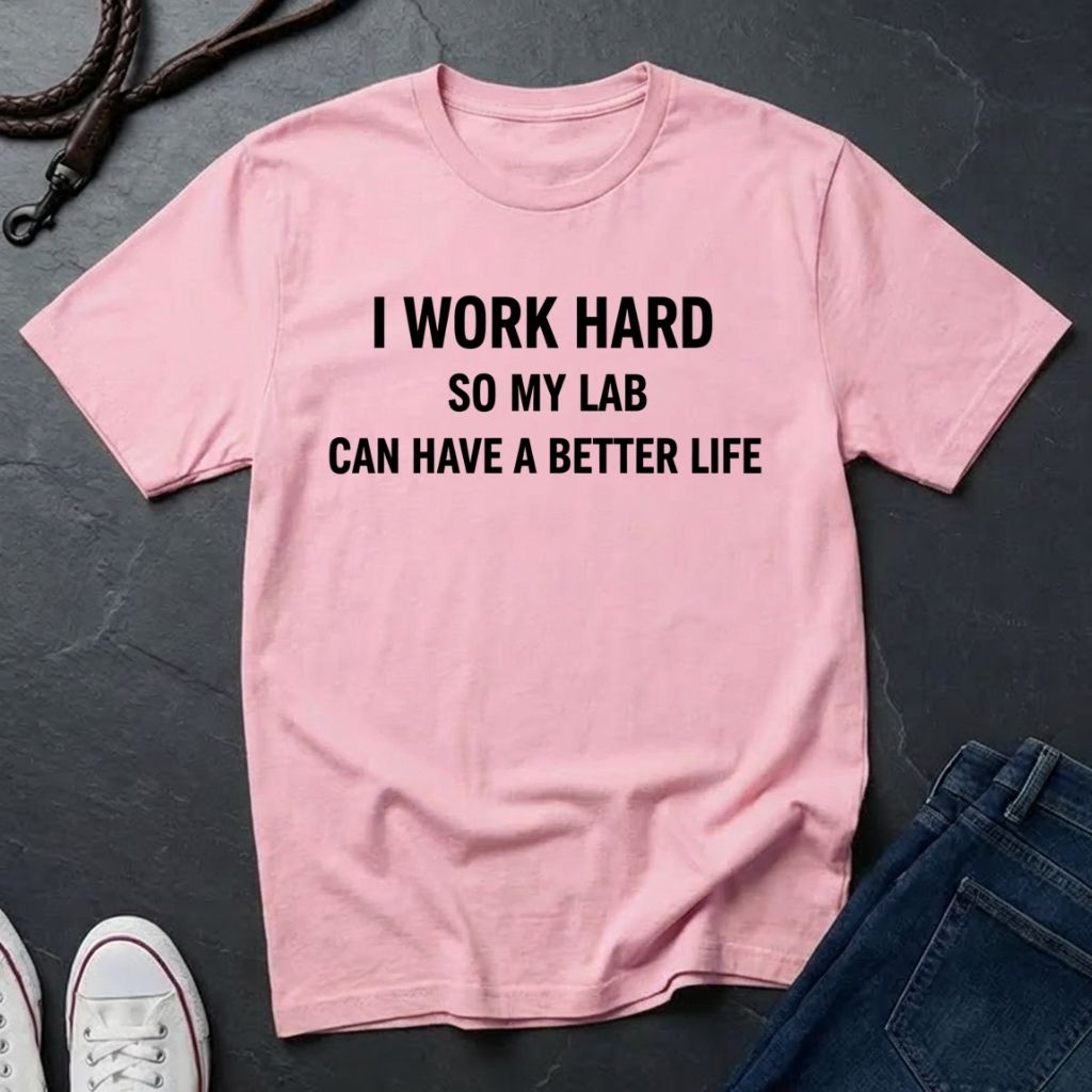 Pink Comfort Colors t-shirt with text 'I work hard so my lab can have a better life' on a dark surface.