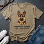 Beige Comfort Colors t-shirt with a German Shepherd graphic and text on a dark surface with shoes and jeans.