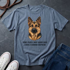 Blue Comfort Colors t-shirt with a German Shepherd graphic and text on a dark surface with shoes and jeans.