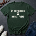 Green Comfort Colors t-shirt with 'My Rottweiler is my best friend' text on a dark surface with shoes and jeans.