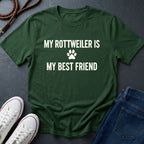 Green Comfort Colors t-shirt with 'My Rottweiler is my best friend' text on a dark surface with shoes and jeans.