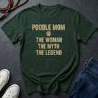 Green Comfort Colors t-shirt with 'Poodle Mom: The Woman, The Myth, The Legend' text on a dark surface with shoes and jeans.