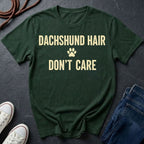 Green Comfort Colors t-shirt with 'Dachshund Hair Don't Care' text on a dark surface with shoes and jeans.