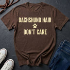 Brown Comfort Colors t-shirt with 'Dachshund Hair Don't Care' text on a dark surface with shoes and jeans.