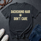 Black Comfort Colors t-shirt with 'Dachshund Hair Don't Care' text on a dark surface with shoes and jeans.