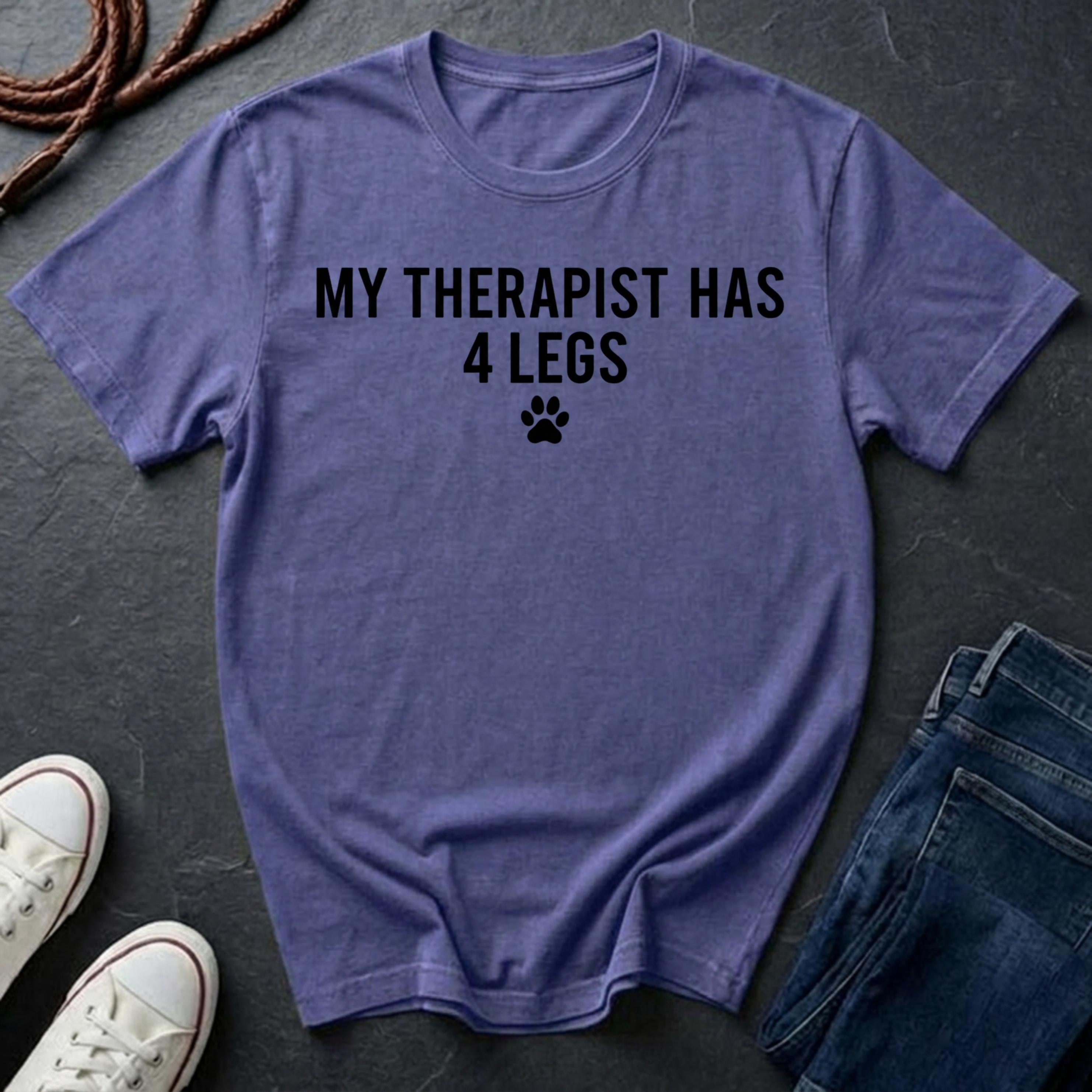Purple Comfort Colors t-shirt with 'My therapist has 4 legs' text on a dark surface with shoes and jeans.
