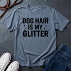 Blue Comfort Colors t-shirt with 'Dog Hair is My Glitter' text on a dark surface with shoes and jeans.