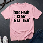 Pink Comfort Colors t-shirt with 'Dog Hair is My Glitter' text on a dark surface with jeans and shoes.