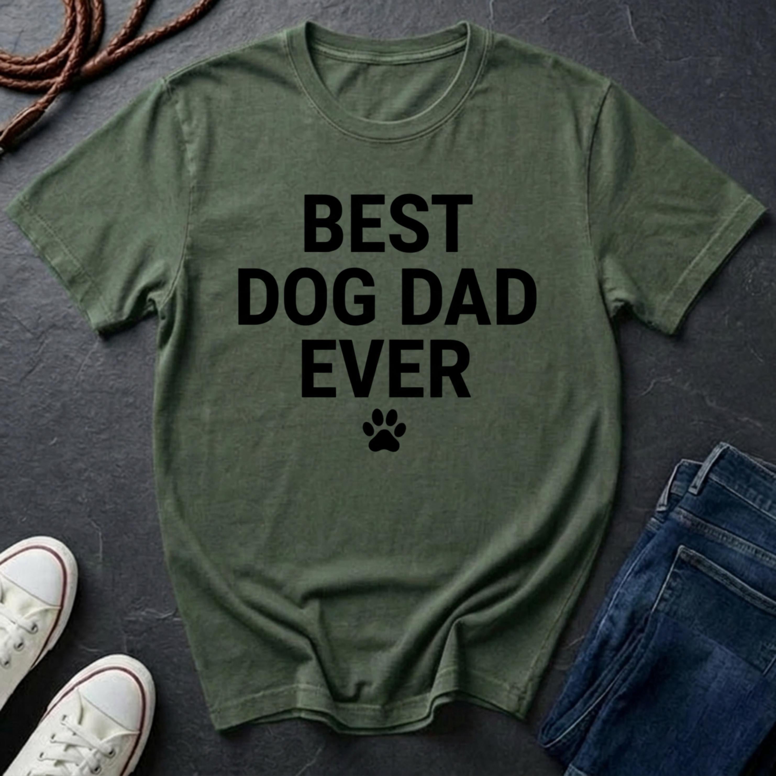 Green Comfort Colors t-shirt with 'Best Dog Dad Ever' text on a dark surface with shoes and jeans.