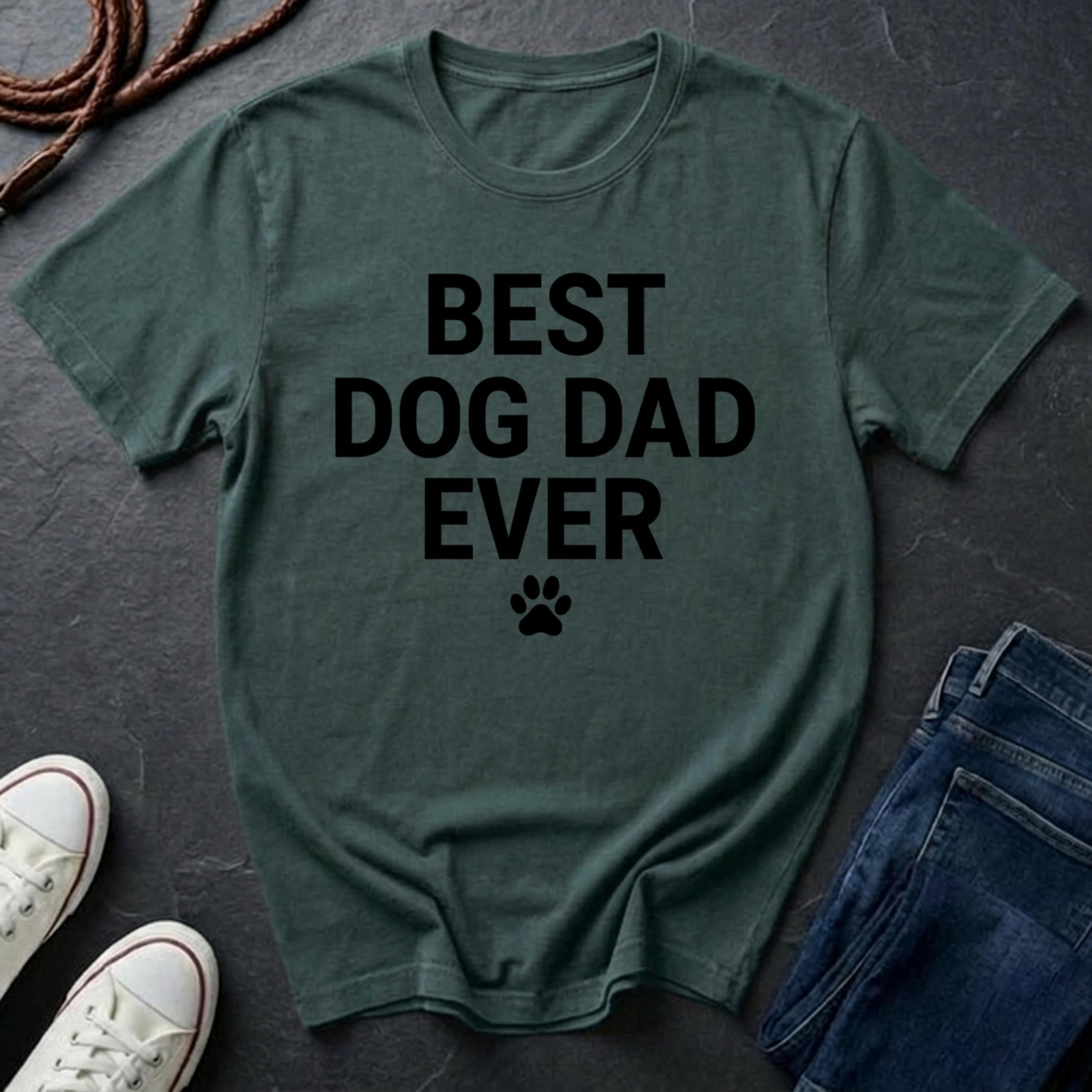 Green Comfort Colors t-shirt with 'BEST DOG DAD EVER' text on a dark surface with shoes and jeans.