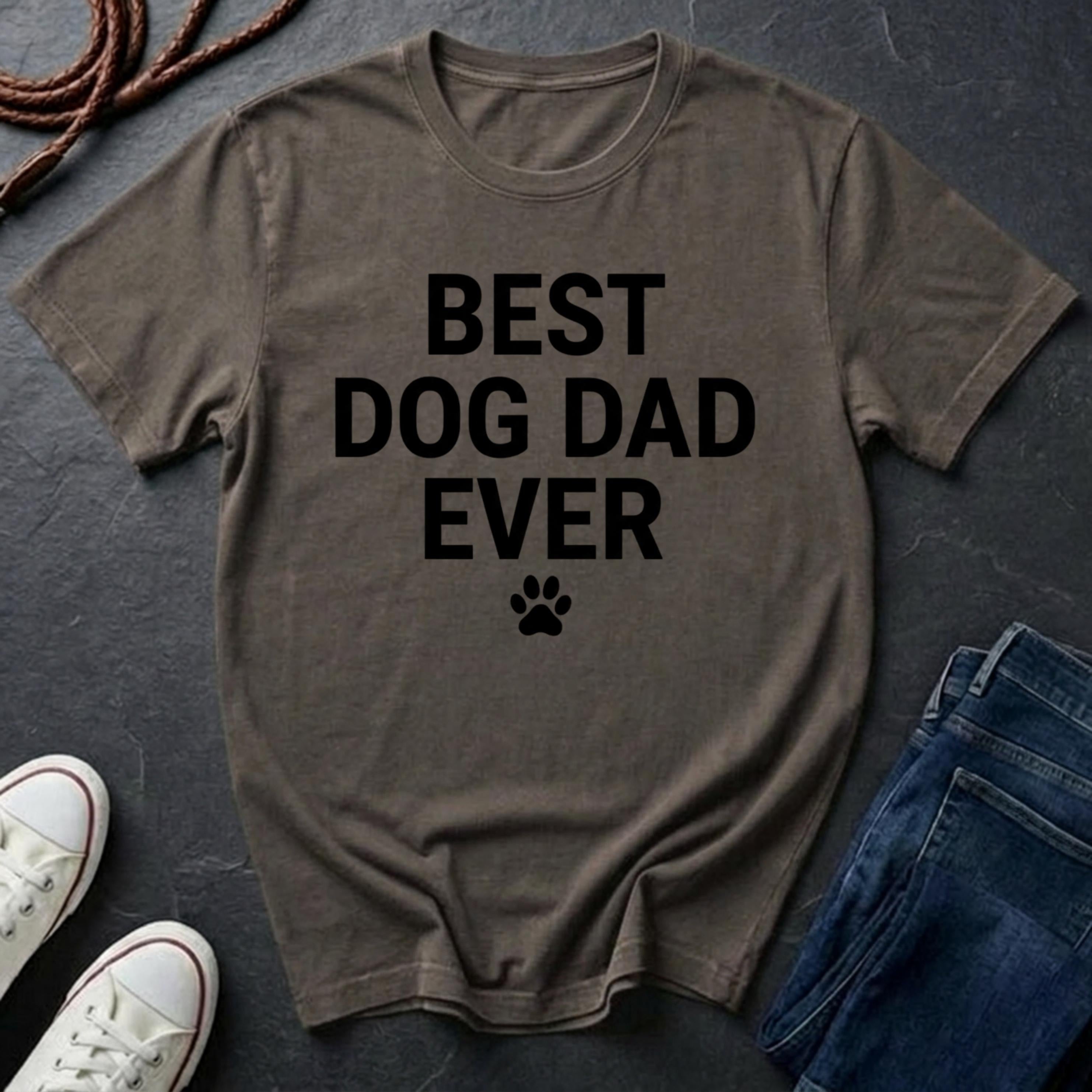 Brown Comfort Colors t-shirt with 'BEST DOG DAD EVER' text on a dark surface with shoes and jeans.