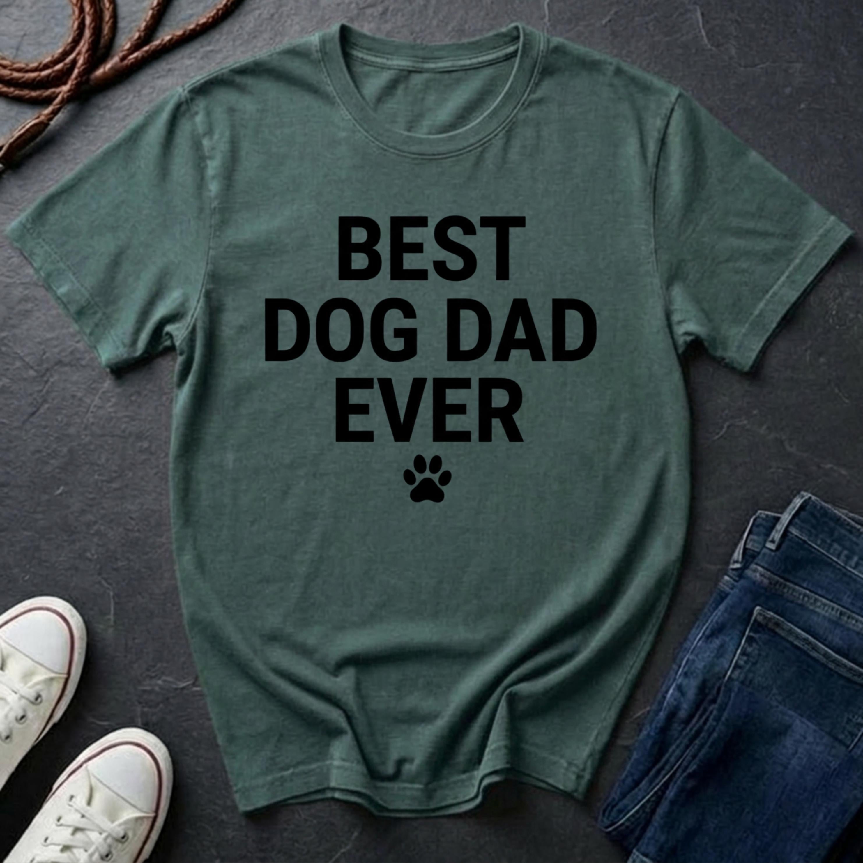 Green Comfort Colors t-shirt with 'BEST DOG DAD EVER' text on a dark surface with shoes and jeans.